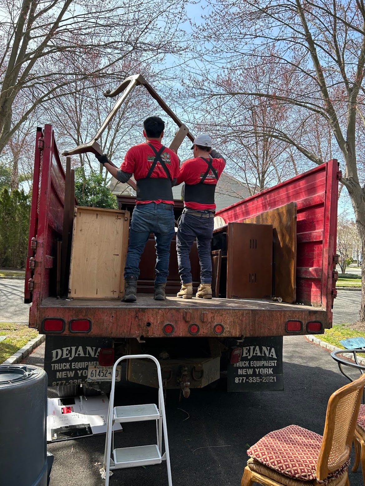 Junk removal workers loading old furniture onto a truck during residential cleanout service in long island