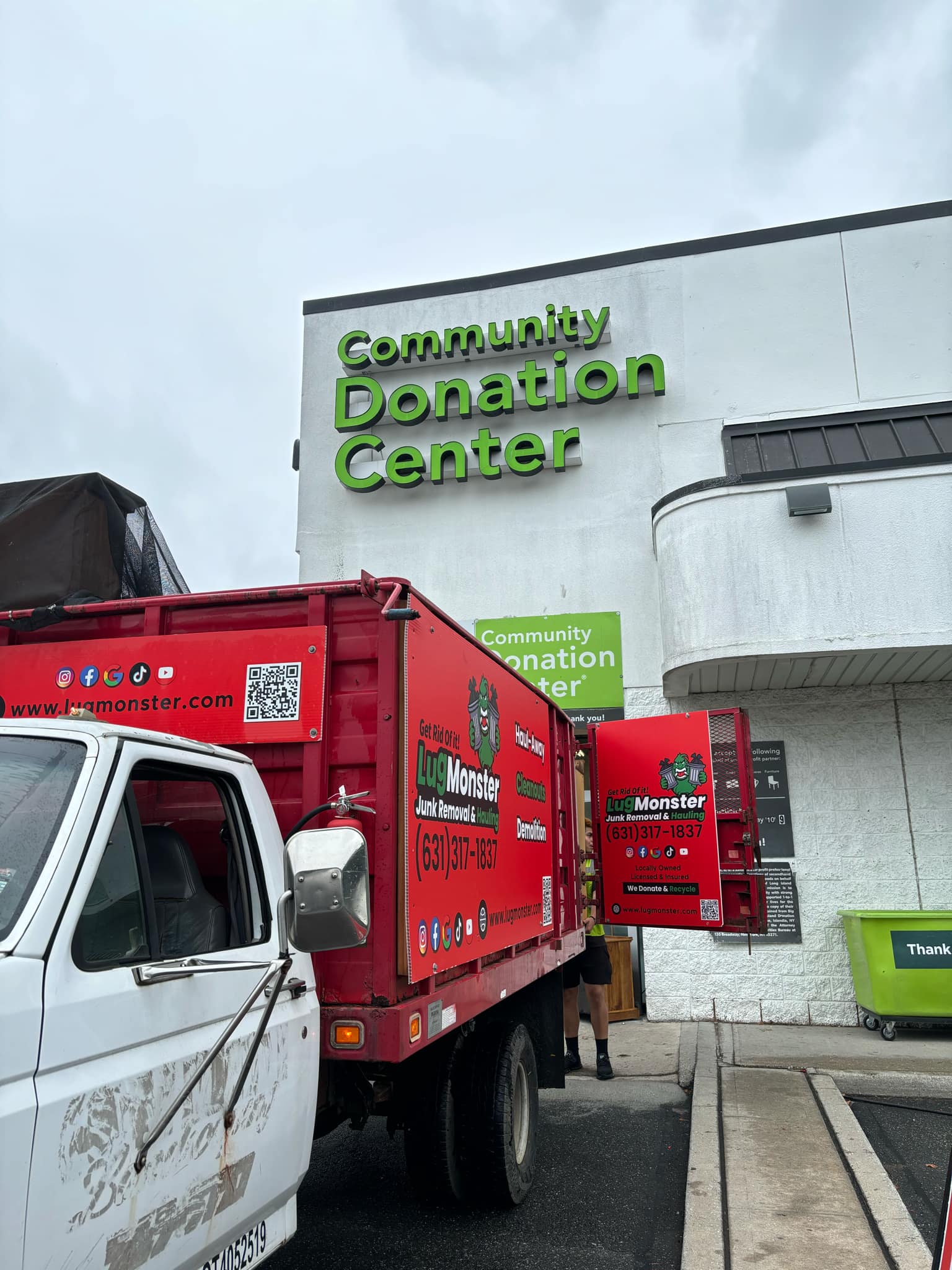 A bright red LugMonster truck parked in front of the Community Donation Center on Long Island, NY, ready for junk removal and donation pickup services.