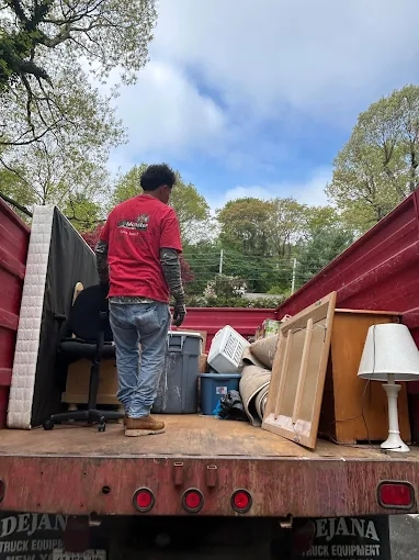 Junk pickup in Long Island NY loading old furniture and household items onto a haul-away truck